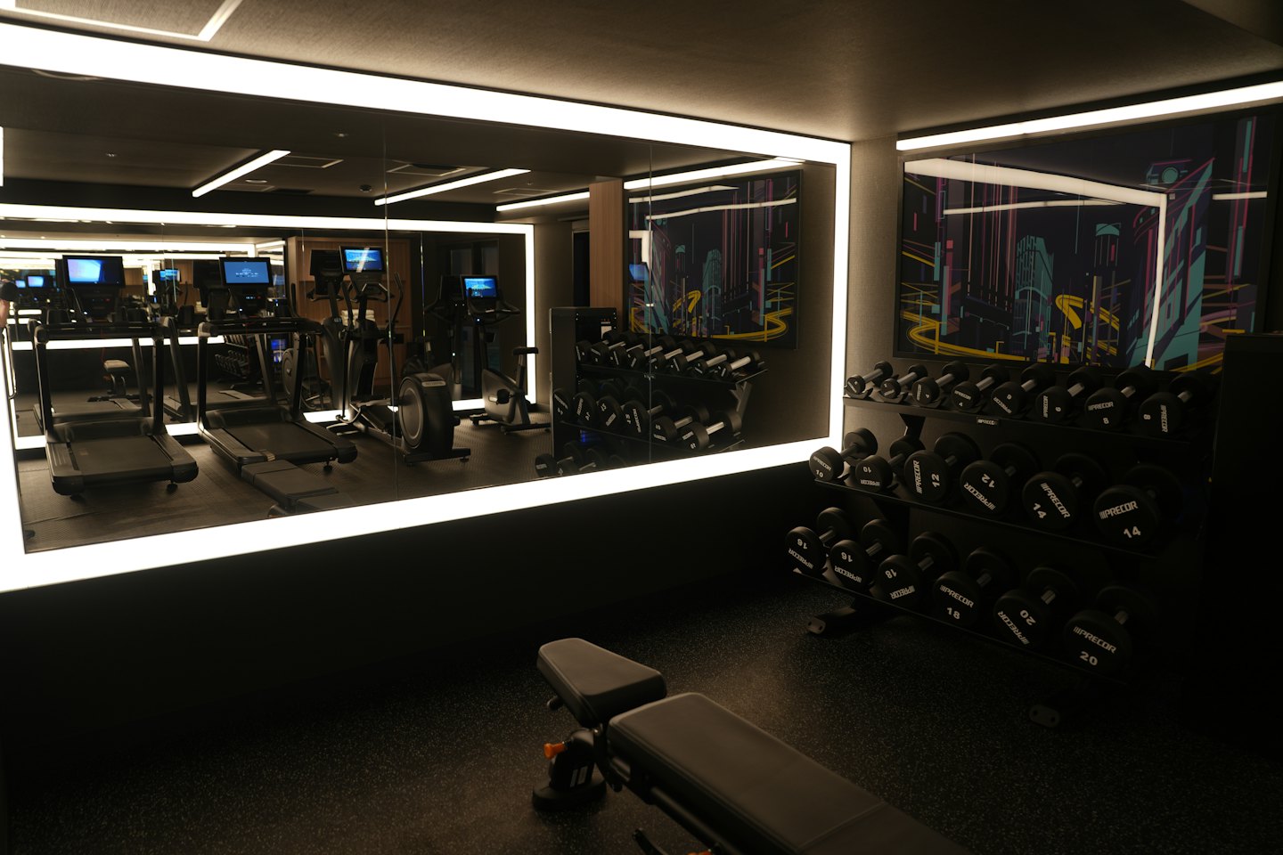 Interior de gimnasio moderno con cintas de correr y mancuernas.